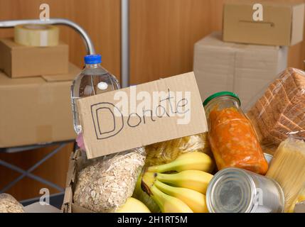 Karton mit verschiedenen Produkten, Obst, Nudeln, Sonnenblumenöl in einer Plastikflasche und Konservierung. Spendenkonzept Stockfoto