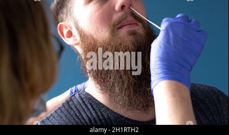 Frau tut Nasenabstrich mit Selbsttest-Kit zu Hause von einem jungen Mann für die Prüfung mögliche Coronavirus-Infektion. Covid-19, Coronavirus, Healht, Selbsttest-CO Stockfoto