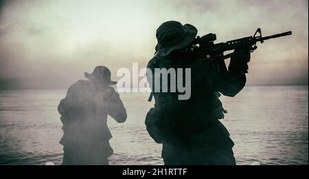 Kommandotruppen, die im Wasser gehen, Armee Spezialeinsätze Streitkräfte Kämpfer schleichen in der Dunkelheit, zielen Sturmgewehre und beobachten Ufer während Ampere Stockfoto