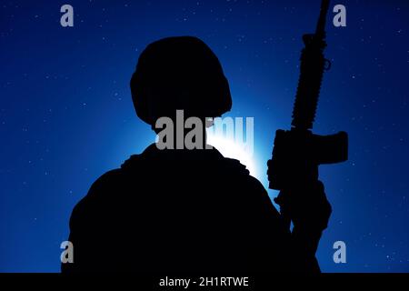 Nacht Silhouette der Armee spezielle Operationen Streitkräfte Soldat mit Dienstgewehr auf dem Hintergrund des Nachthimmels mit Mond und Sternen stehen. Moderne Kriegsführung Stockfoto