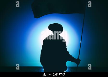 Silhouette eines Soldaten der Armee, Kommandojäger Spezialeinheiten Infanterist auf dem Hintergrund des Sonnenuntergangs Himmel winken auf Fahnenmast Flagge. Militärischer Sieg Stockfoto
