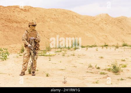 Ausgerüstet und bewaffnete Spezialeinheiten Soldat, Armee Ranger in der Wüste mit Kopieplatz stehen. Konzept der militärischen Anti-Terrorismus-Operationen, speziell Stockfoto