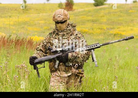 Spezialwehrsoldat mit Scharfschützengewehr geht über das Sommerfeld Stockfoto