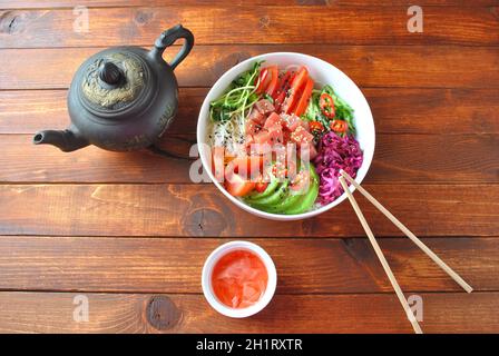 Thunfisch-Schüssel mit Kristallnudeln, frischem Rotkohl, Avocado, Kirschtomaten. Food Concept Poke Bowl auf Holzhintergrund. Bio-Lebensmittel. Frisches Meer Stockfoto