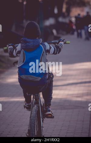 Kleiner Junge, der mit seinem Fahrrad auf dem Bürgersteig einen Wheelie macht Stockfoto