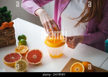 Bild von Frauenhänden, die Orangen zusammendrücken, um einen Saft voller Vitamine zu machen. Gesunde Ernährung. Fruchtsaft. Stockfoto