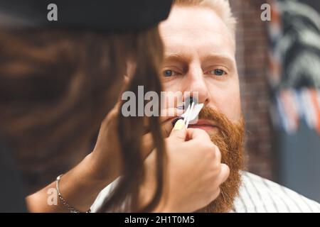 Bartmodellierung im Barber-Shop, Entfernen von Haaren aus der Nase und Ohren mit Wachs, männliche Schönheit und Pflege-Konzept Stockfoto