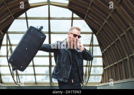 Stilvoll gekleideter junger Mann mit Bart lernt die guten atemberaubenden Nachrichten per Telefon. Lifestyle emotionales Stadtportrait. Stockfoto