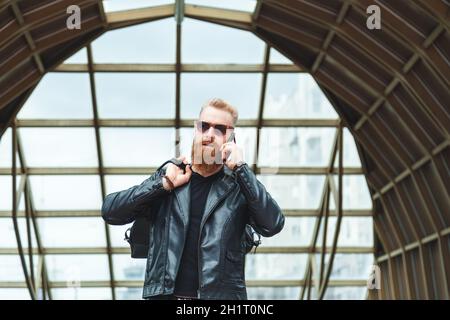 Stilvoll gekleideter junger Mann mit einem Bart, der am Telefon spricht Stockfoto