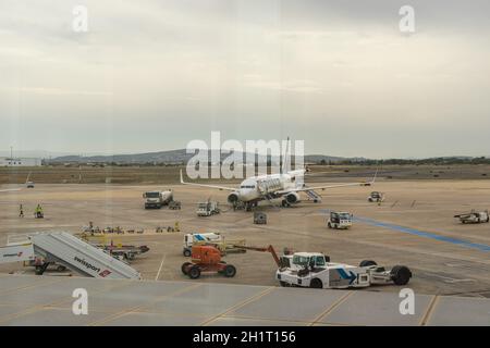 VALENCIA, SPANIEN - 06. Sep 2021: Eine Aufnahme eines weißen Flugzeugs neben Fahrzeugen auf dem Flughafen von Valencia, Spanien Stockfoto