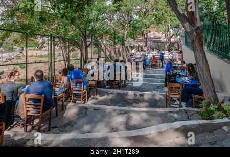 Die Menschen genießen Erfrischungen in einem traditionellen griechischen Café im Freien auf dem Hügel der Akropolis im Stadtteil Plaka. Stockfoto