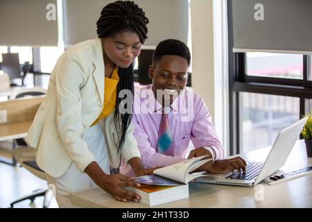 Zwei junge geschäftsanraine aus afrika diskutieren über einen Laptop. Stockfoto