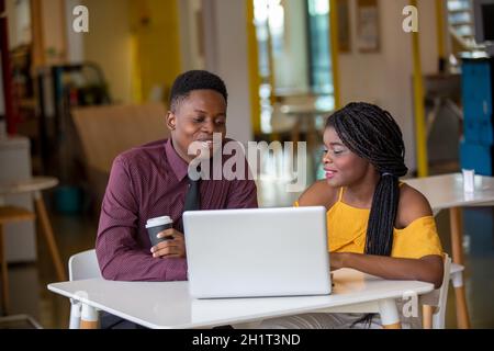 Zwei junge geschäftsanraine aus afrika diskutieren über einen Laptop. Stockfoto
