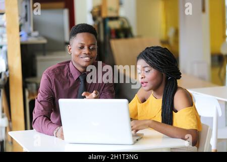 Zwei junge geschäftsanraine aus afrika diskutieren über einen Laptop. Stockfoto