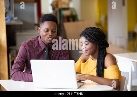 Zwei junge geschäftsanraine aus afrika diskutieren über einen Laptop. Stockfoto