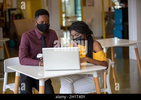 Zwei junge geschäftsanraine aus afrika diskutieren über einen Laptop. Stockfoto