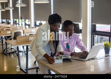 Zwei junge geschäftsanraine aus afrika diskutieren über einen Laptop. Stockfoto
