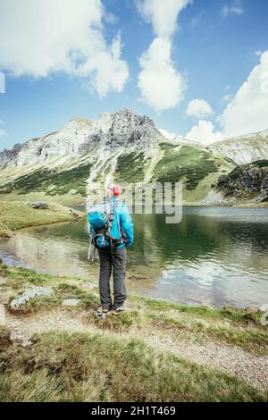 Weibliche blond Bergsteiger mit Rucksack ist die Aussicht genießen Stockfoto