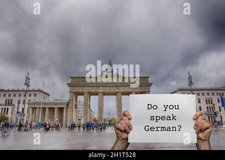 Ein Mann, der ein Schild mit dem Brandenburger Tor in der Hand hält Berlin im Hintergrund Stockfoto