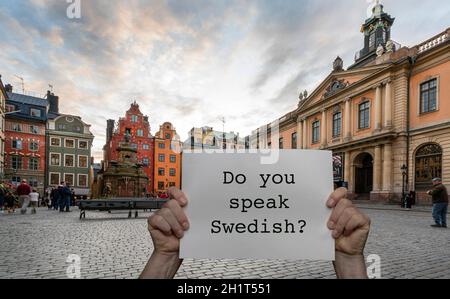 Ein Mann, der ein Schild mit dem Stortorget-Platz in der Hand hält Stockholm im Hintergrund Stockfoto