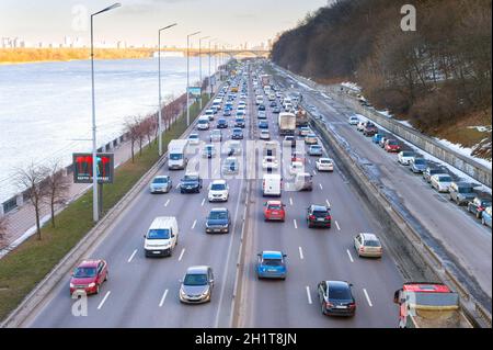 KIEW, UKRAINE - 03. MÄRZ 2021: Verkehr auf der Uferstraße bei Sonnenuntergang. Kiew ist die Hauptstadt der Ukraine Stockfoto