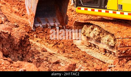 Backhoe working by digging soil at construction site. Bucket of backhoe digging soil. Crawler excavator digging on dirt. Excavating machine. Earth mov Stockfoto