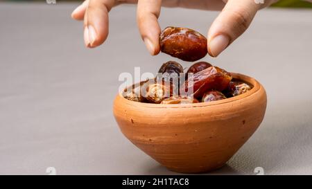 Datteln in Tonschüssel auf dem Hintergrund. Getrocknete Datteln Frucht. Stockfoto