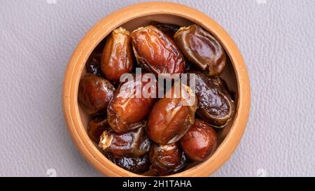 Datteln in Tonschüssel auf dem Hintergrund. Getrocknete Datteln Frucht. Stockfoto