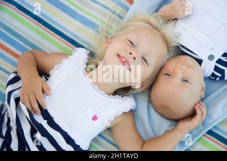 Niedliche kleine Schwester Verlegung als nächstes ihr Baby Bruder auf Decke. Stockfoto