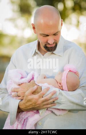 Junge hübscher Vater hält sein neugeborenes Mädchen außerhalb. Stockfoto