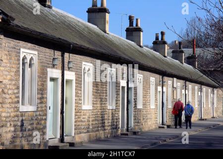 Zufrieden in den letzten Jahren: Ein älteres Paar schlendert an Lady Lumleys Almshouses in Thornton le Dale, North Yorkshire, England, vorbei Stockfoto