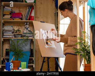 Die Künstlerin greift zu Hause auf eine Staffelei zurück Stockfoto