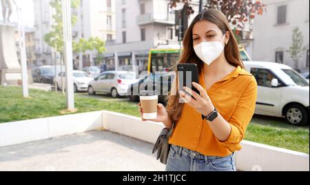 Geschäftsfrau mit KN95 FFP2 Gesichtsmaske stehend und mit Smartphone-App in der Stadt Straße Stockfoto