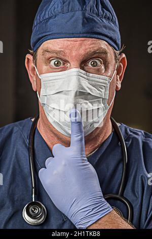 Betäubt Arzt oder Krankenschwester mit Finger vor Mund tragen Schutzkleidung tragen und Stethoskop. Stockfoto