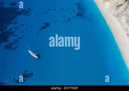Lefkada, Griechenland. Abgelegener weißer Egremni-Strand mit einsamem Luxus-Yacht-Boot an der türkisfarbenen Bucht am Ionischen Meer Stockfoto