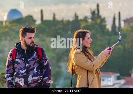 ATHEN, GRIECHENLAND, DEZEMBER - 2019 - eine Frau, die ein Selfie auf dem philopappos-Hügel macht, einem berühmten Aussichtspunkt auf einer Akropolis. Stockfoto