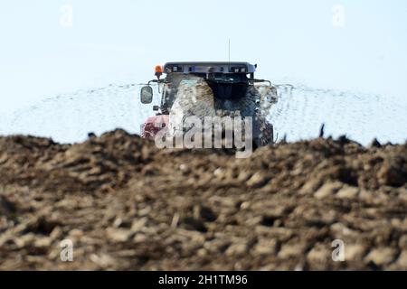 Ein Traktor mit einem Güllefass auf einem Acker - Ein Traktor mit einem Gülletanker auf einem Feld Stockfoto