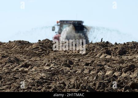 Ein Traktor mit einem Güllefass auf einem Acker - Ein Traktor mit einem Gülletanker auf einem Feld Stockfoto