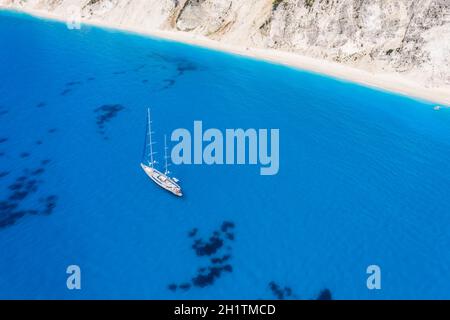 Lefkada, Griechenland. Abgelegener weißer Egremni-Strand mit einsamem Luxus-Yacht-Boot an der türkisfarbenen Bucht am Ionischen Meer Stockfoto