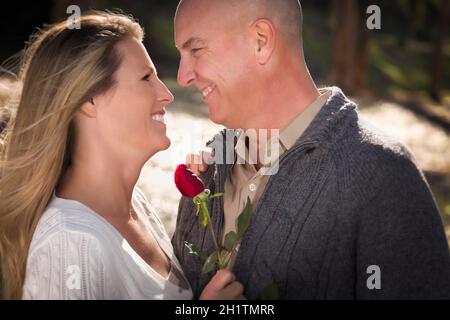 Attraktives junges Paar, das Pullover mit Rose im Park trägt. Stockfoto