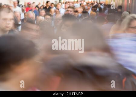 Menschenmenge, die auf der Stadtstraße läuft - Bewegung verschwommen Bild mit nicht erkennbaren Gesichtern Stockfoto