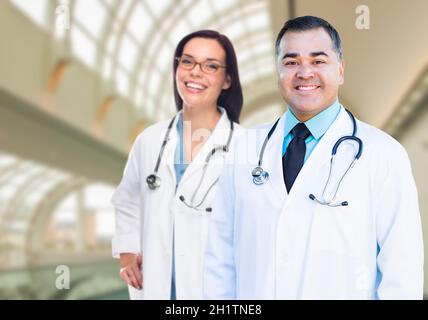 Zwei männliche und weibliche Ärzte oder Krankenschwestern stehen innen Krankenhausgebäude. Stockfoto