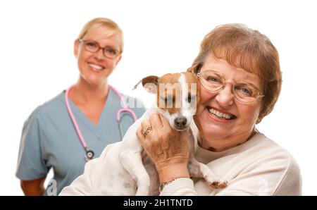 Glückliche ältere Frau mit ihrem Hund und Tierarzt hinter isoliert auf weißem Hintergrund. Stockfoto