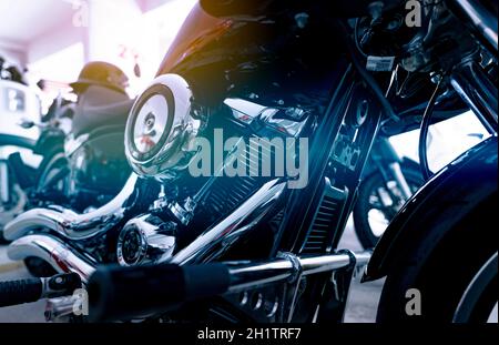 Selektiver Fokus auf einen Motorradmotor. Nahaufnahme des Auspuffrohrs des Motorrads, des Motorschutzes, des Luftfilters und des hinteren Bremspedals. Motorradindustrie. Glänzender Lm Stockfoto