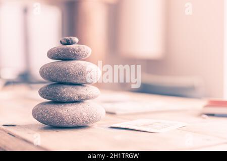 Feng Shui: Steinkairn im Vordergrund, verschwommenes Wohnzimmer im Hintergrund. Balance und Entspannung. Stockfoto