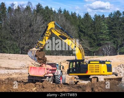 Gelber Erdbeweger, der einen Lastwagen auf einer Baustelle füllt Stockfoto