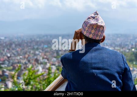 KATHMANDU, NEPAL - CA. MÄRZ 2015: Nepalesischer Mann mit Topi betrachtet die Stadt Kathmandu von Swayambhunath aus. Stockfoto