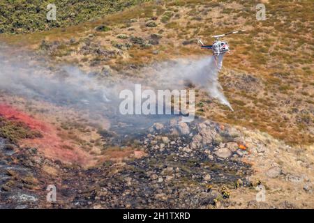 Winchester, CA USA - 14. Juni 2020: CAL Fire Hubschrauber wirft Wasser auf einem trockenen Bergfeuer in der Nähe von Winchester, Kalifornien. Stockfoto