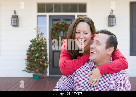 Glückliches Junges Paar lachend auf der Veranda des Hauses mit Weihnachtsschmuck. Stockfoto