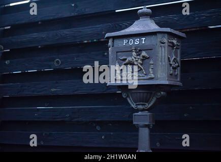 Vintage-Mailbox. Schöne altmodische Mailbox schwarz. Mailbox auf dem Hintergrund eines schwarzen Zauns Stockfoto